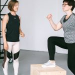 Fitness coach guides a woman in workout indoors. Focus on exercise and healthy lifestyle.