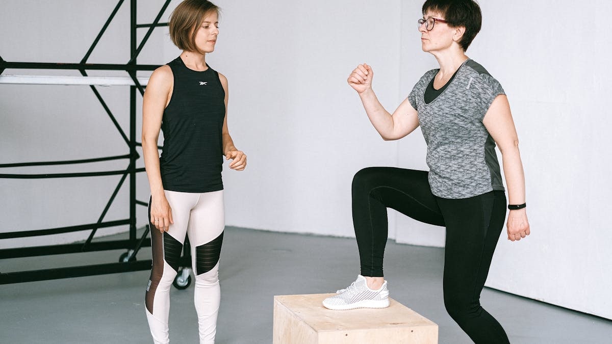 Fitness coach guides a woman in workout indoors. Focus on exercise and healthy lifestyle.