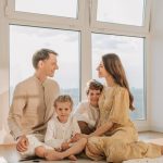 A joyful family sits together in a sunlit living room, fostering warmth and connection.